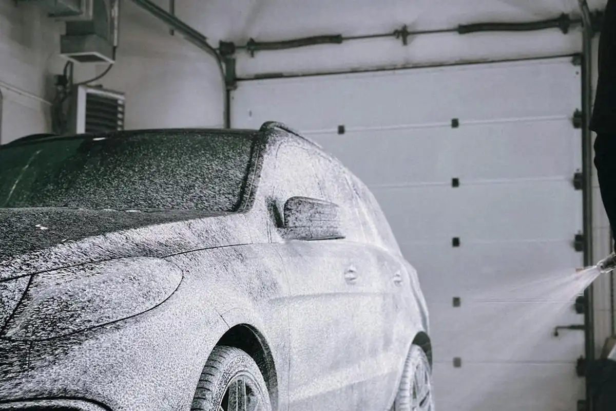 A car parked in a garage covered in white absorbent powder used to soak up a gasoline spill from the floor and vehicle.