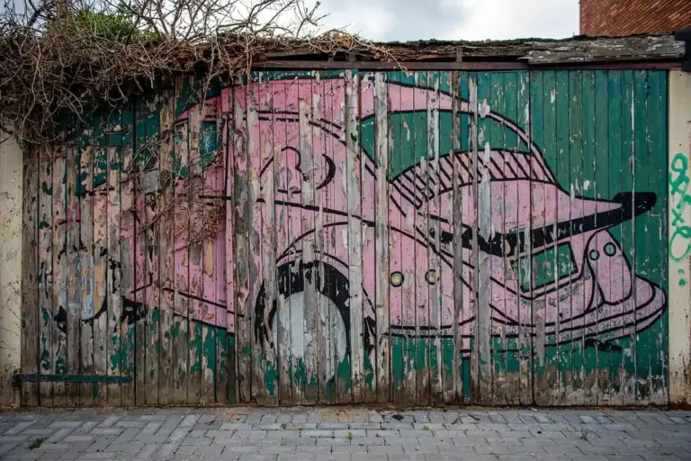 Graffiti-covered wooden garage door with a colorful mural of a car.