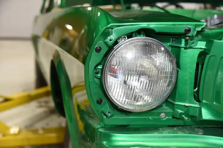 Close-up of a green vintage car headlight in a garage setting