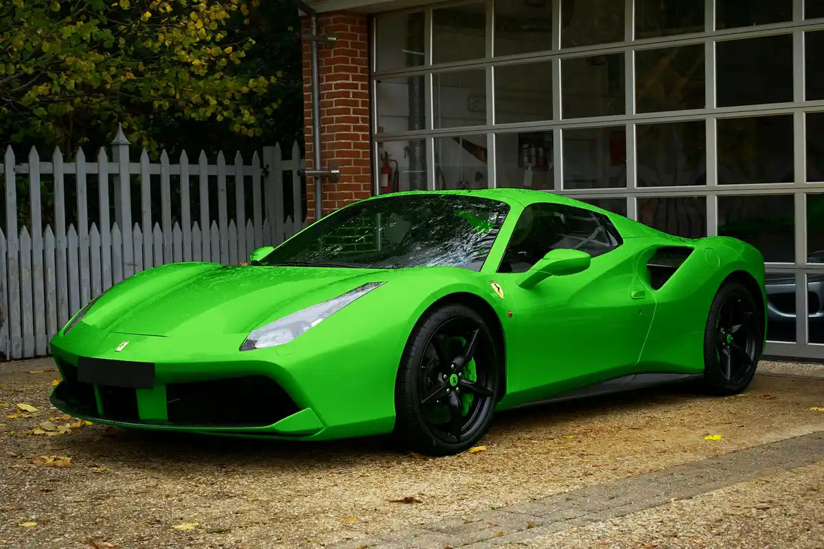 Bright green sports car parked in front of a residential garage.