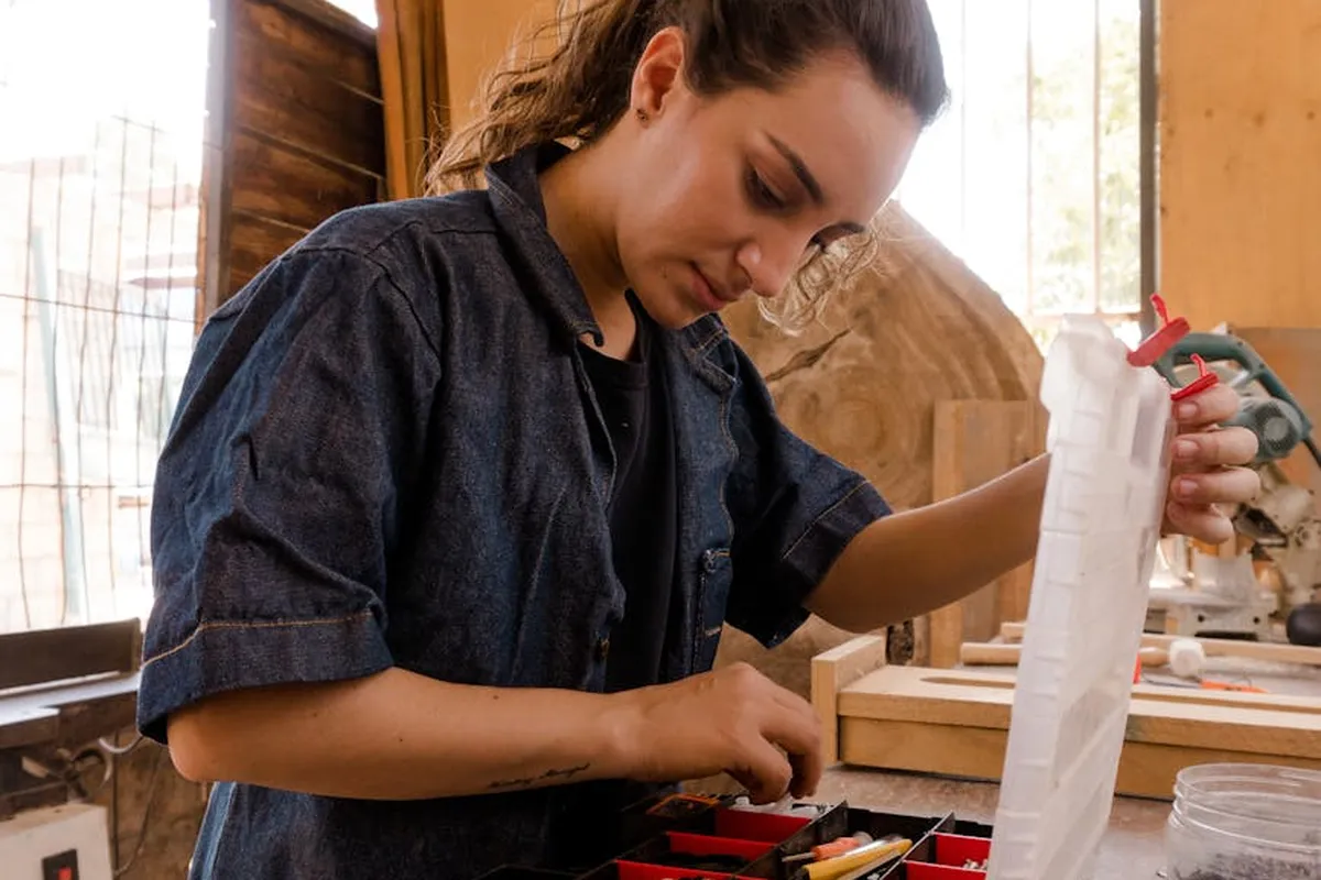 A person organizing tools in a home workshop with a wooden workbench and assorted equipment.