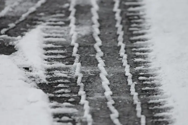 Snow-covered pavement with parallel tire tracks in a cold, wintry setting