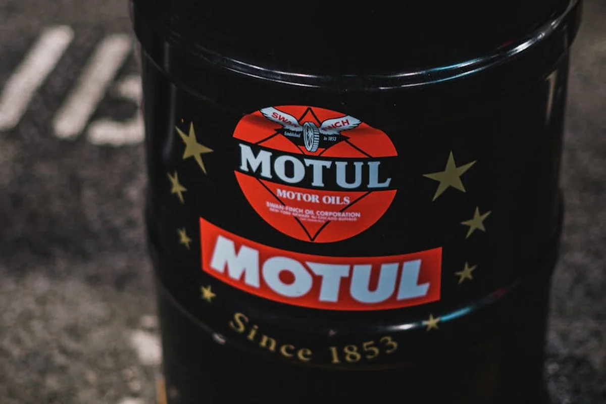 Close-up of a Motul motor oil barrel with logo on a dark garage floor