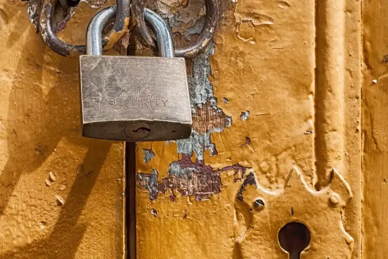 Close-up of a metal padlock securing a weathered wooden door, illustrating security concerns relevant to storing valuables in a garage.
