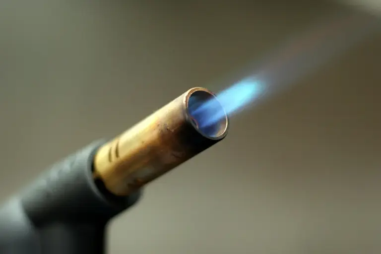 Close-up of a propane torch nozzle emitting a blue flame