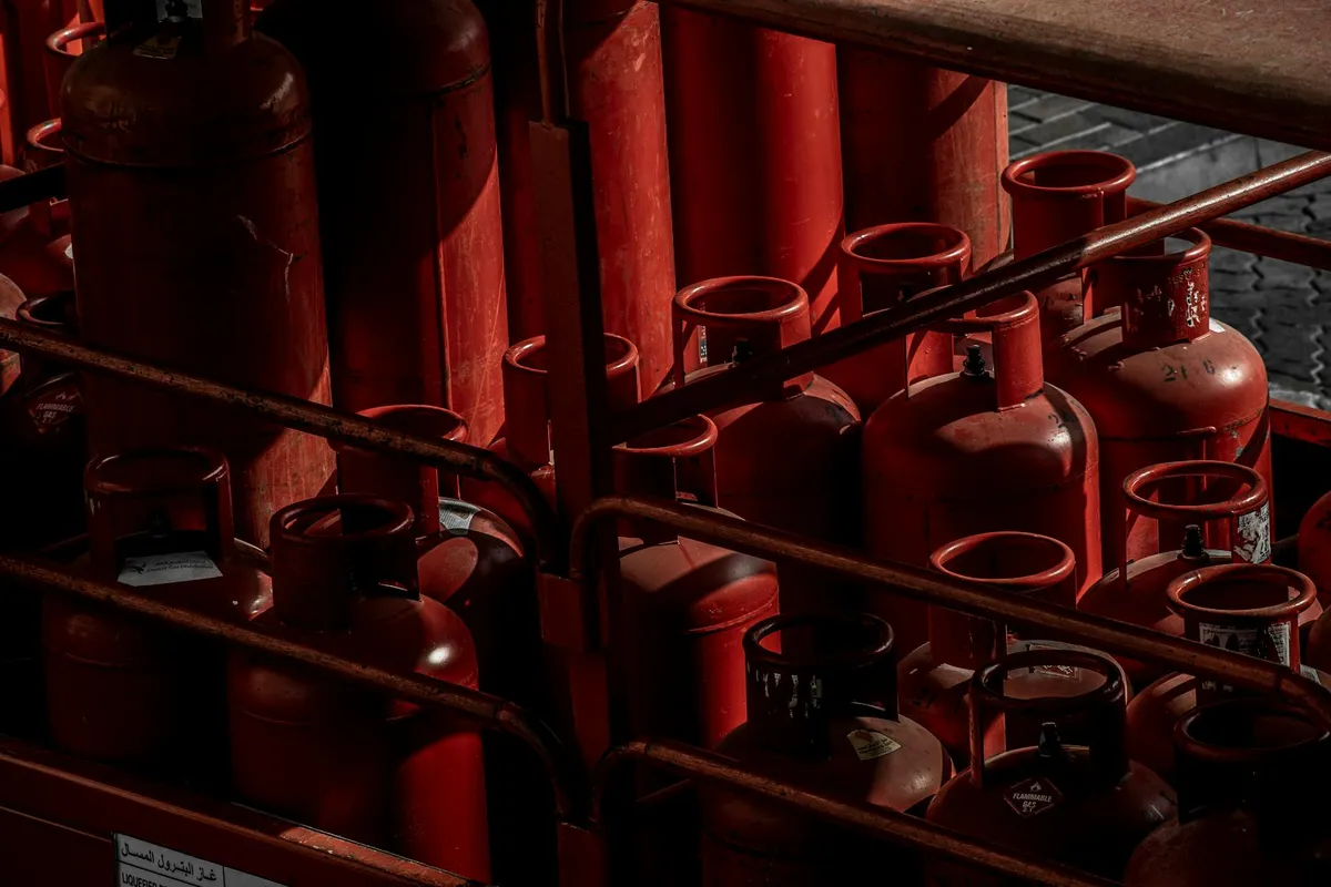 Row of red propane cylinders stored in a rack in a garage or workshop.