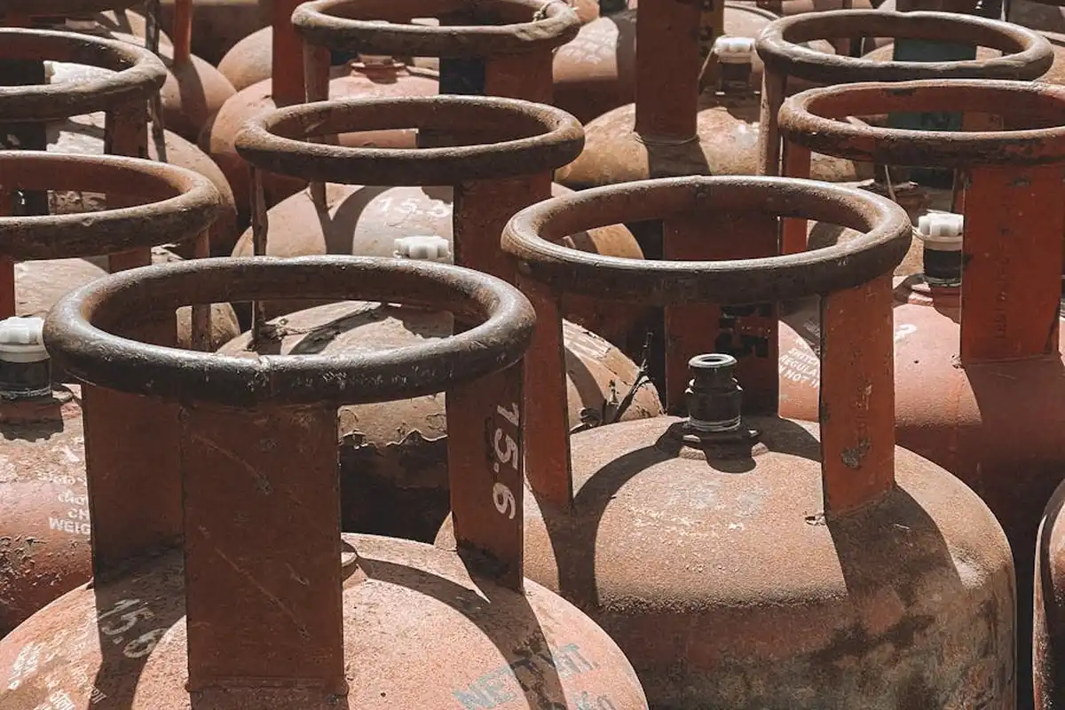 Close-up of multiple rusty propane tanks with valves in a garage or storage area.