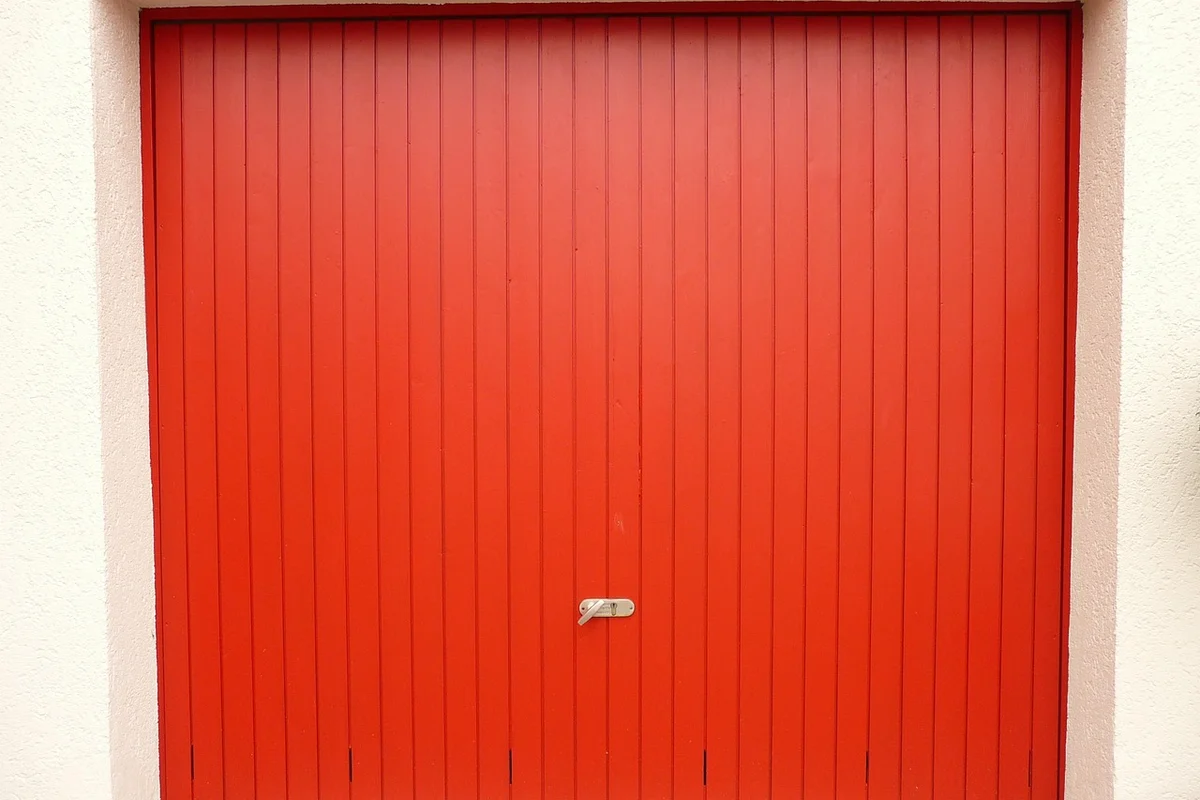 Red garage door with vertical panels and a small metal latch in the center.