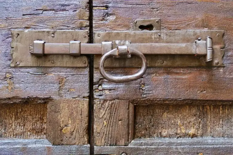 Close-up of a rustic metal ring latch mounted on weathered wooden barn door
