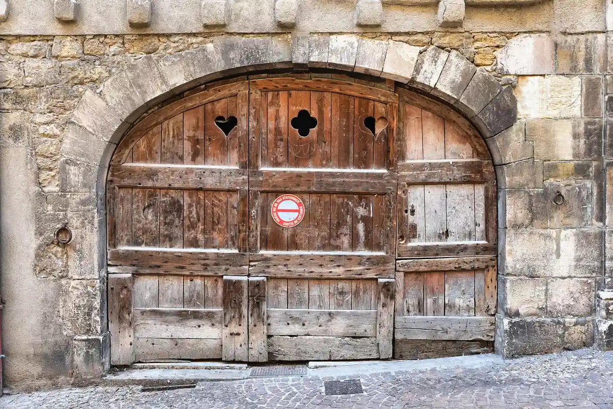 Weathered wooden arched garage door set into a rough stone wall.