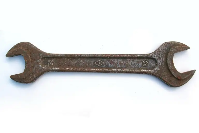 Rusted open-end wrench on a white surface.