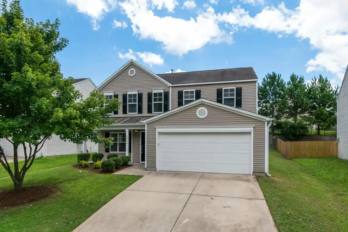 Front view of a suburban home with a two-car attached garage, manicured lawn, and a paved driveway.
