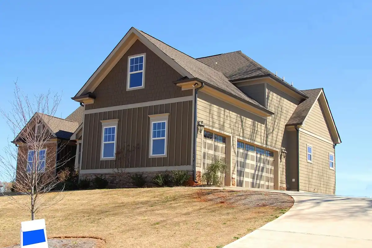 Exterior of a modern suburban house with an attached two-car garage and a sloped concrete driveway.