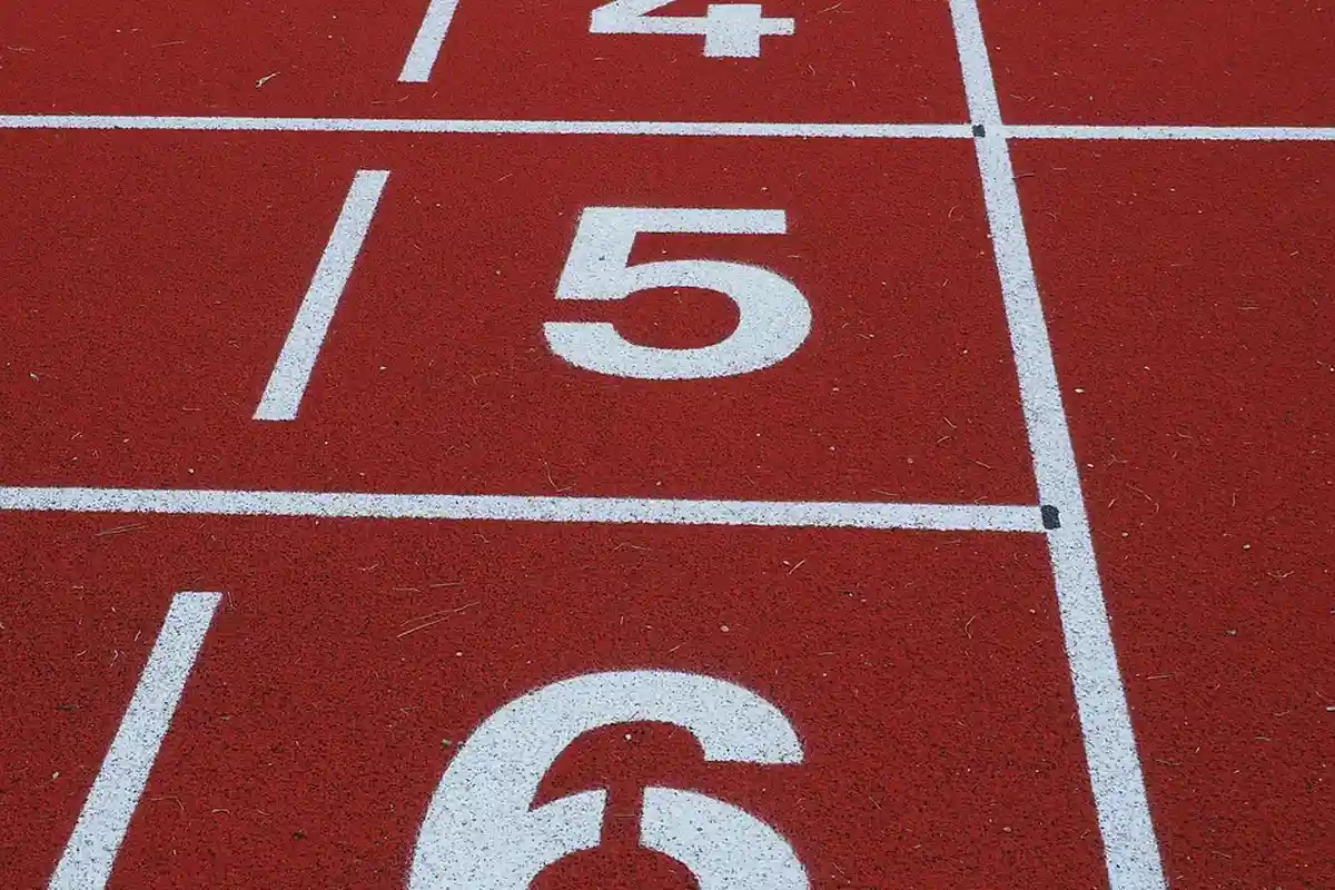 Close-up of white number 5 on a red running track with lane lines