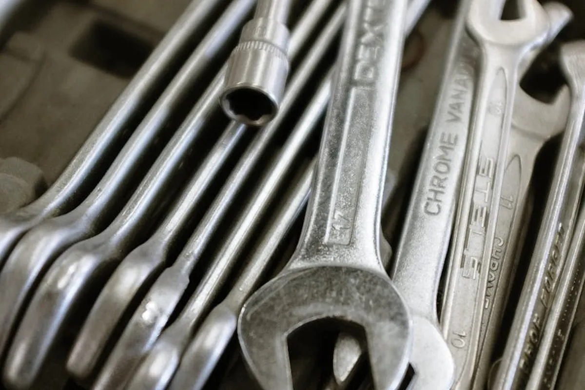 Close-up of metal wrenches and sockets laid out on a workbench.
