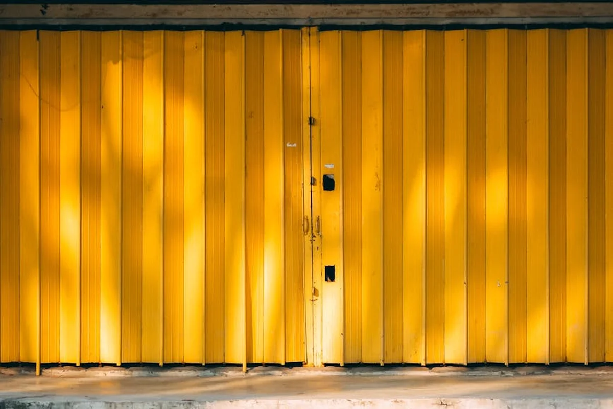 Yellow vertical-panel garage door with a small entry door in the center