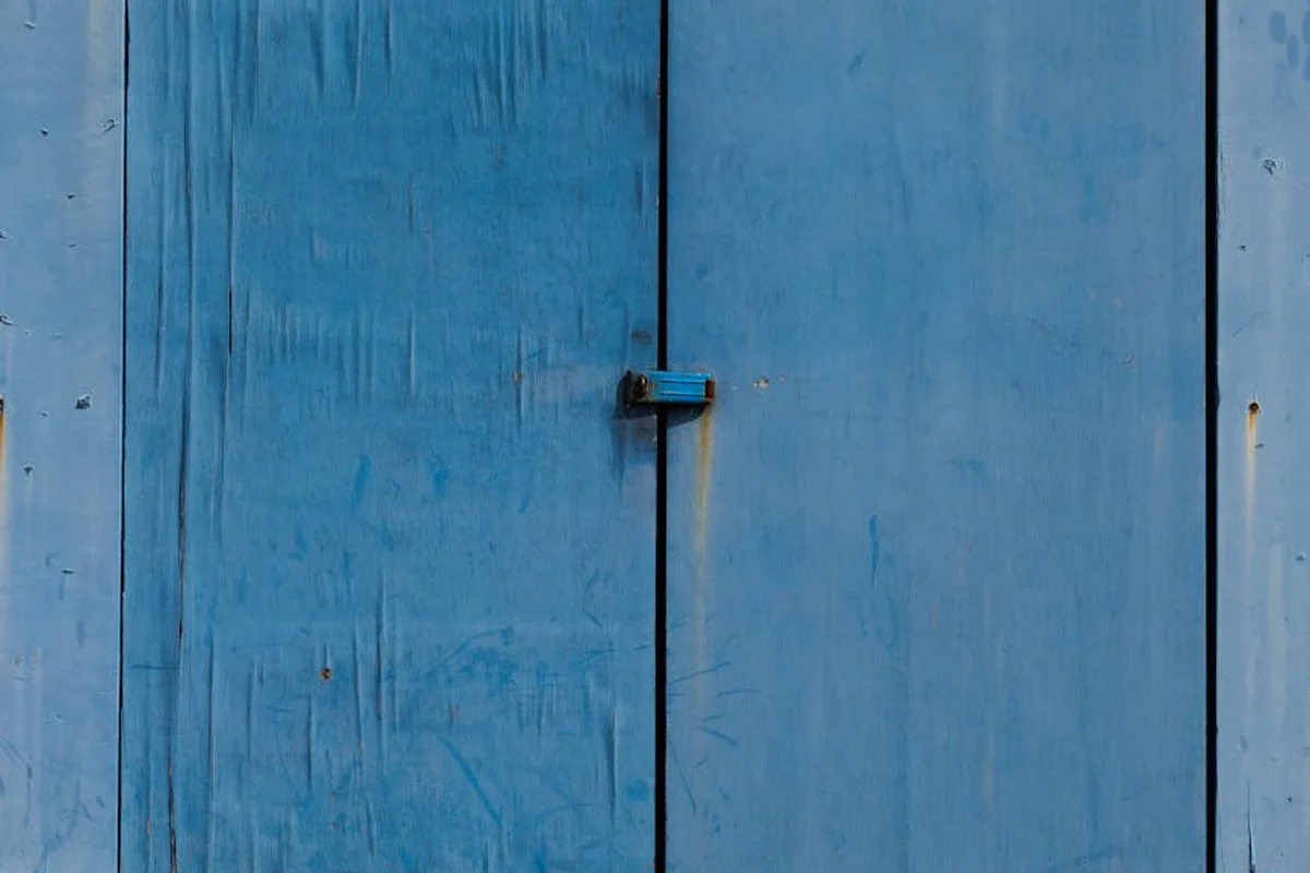 Close-up of a blue wooden garage door with a small latch in the center.