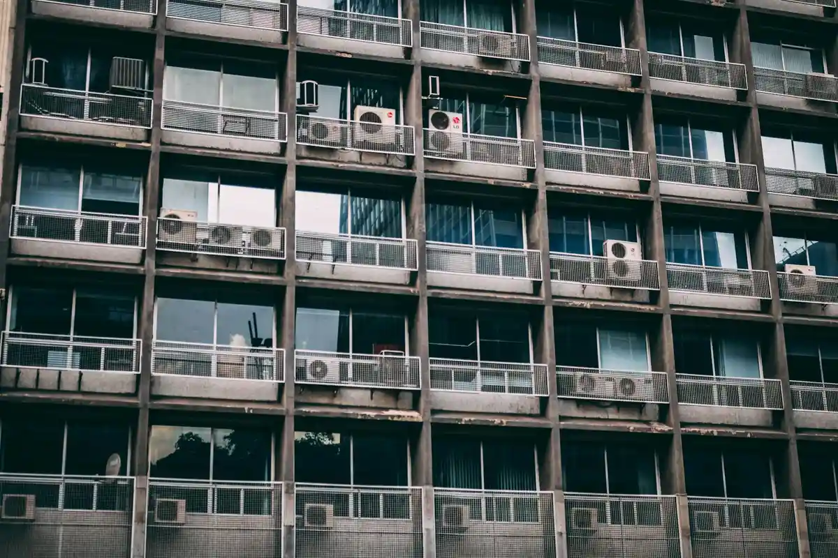 Facade of a multi-story building with numerous window air conditioners installed in most windows.