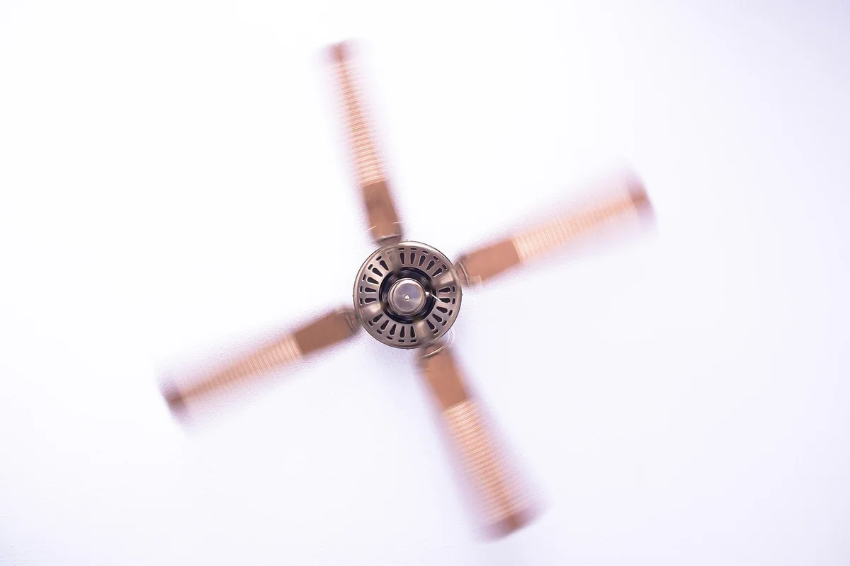 Blurry ceiling fan blades with copper-colored blades seen from below.