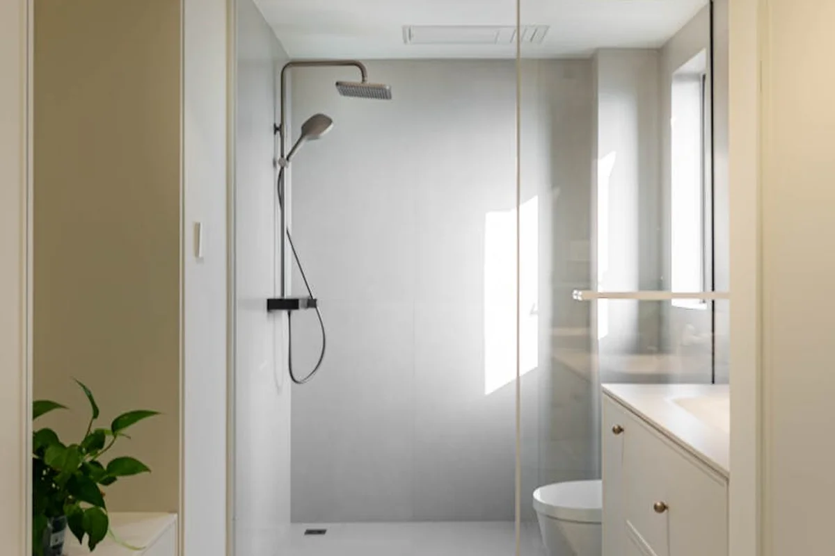 Modern bathroom with a glass-enclosed shower, white vanity, and natural light, illustrating a compact, climate-controlled garage apartment.