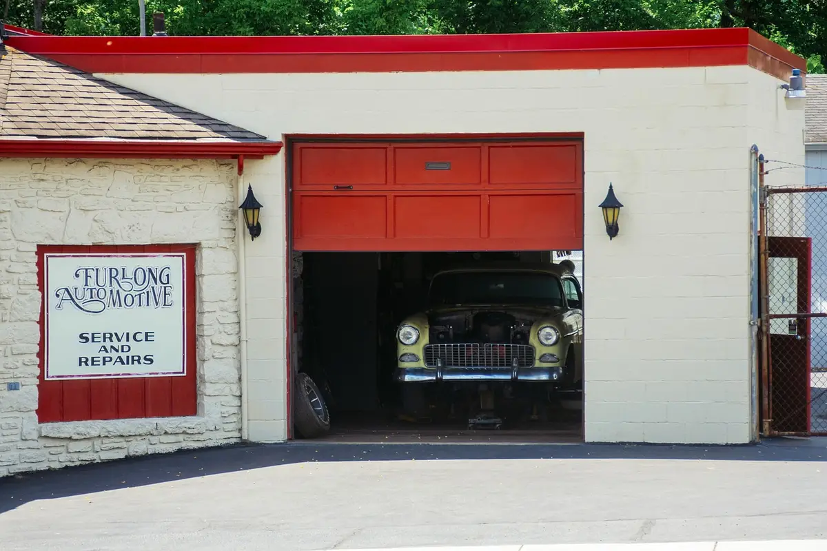Vintage car in a garage with an open door and red trim, illustrating moisture control.
