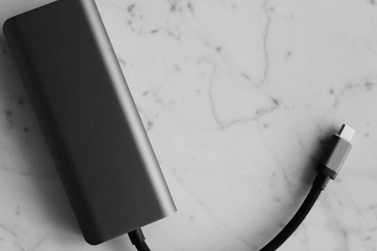 Close-up of a black rectangular garage door opener battery backup with a connecting cable on a light marble surface.