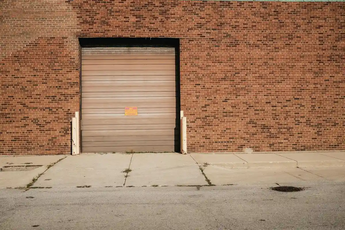 Closed garage door on a brick building with a concrete driveway, ready for maintenance.