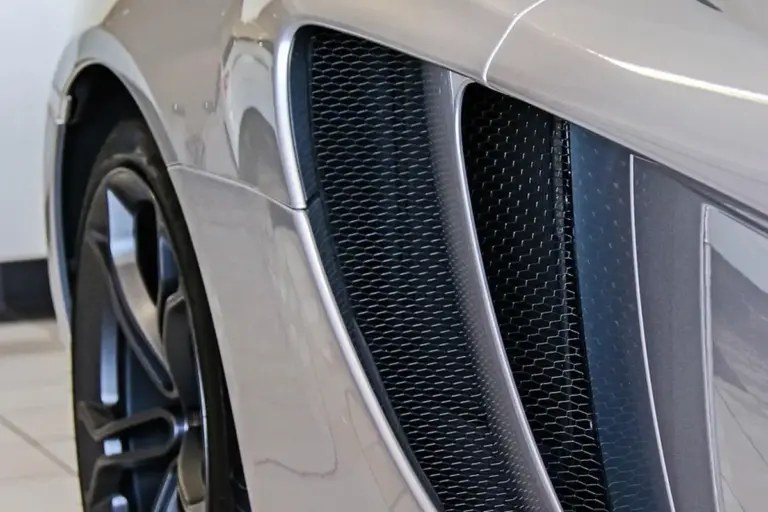 Close-up of a silver sports car's front grille and bumper, suggesting a garage setting for smart climate automation.