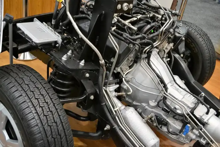 Close-up view of a car's exposed engine and drivetrain with wheels mounted in a workshop.