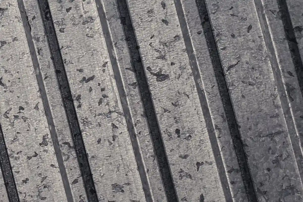Close-up of a weathered ribbed metal surface with vertical ridges, suggesting prep work for painting a garage wall.