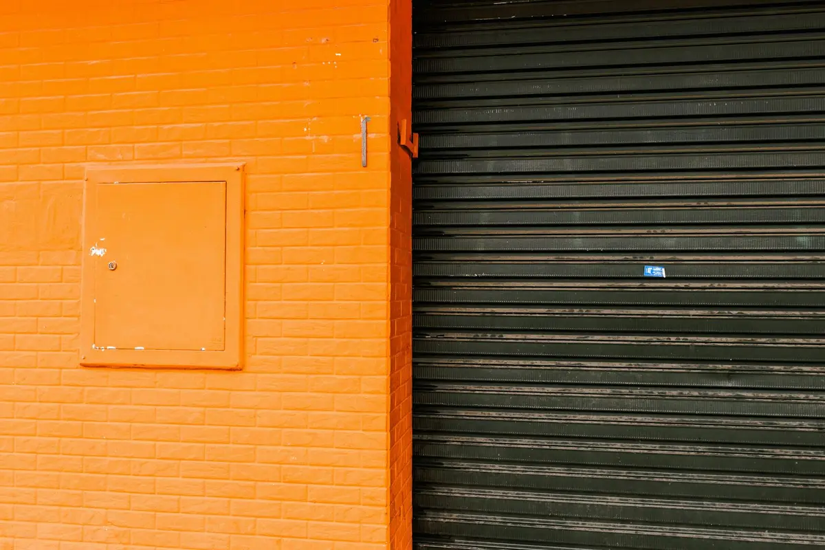 Orange-painted brick wall adjacent to a dark green garage door, illustrating contrasting wall surfaces.