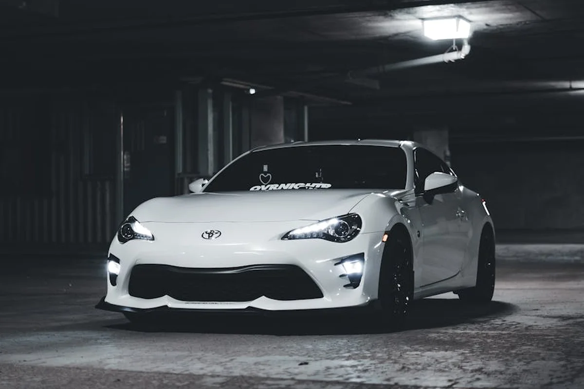 White sports car parked in a dimly lit concrete garage, illustrating the importance of sealing and insulation considerations in a garage build-out.