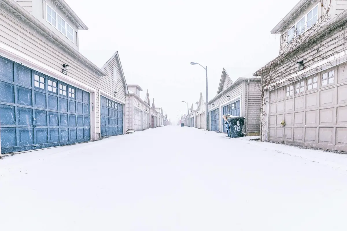 Snow-covered suburban street with closed garage doors on both sides