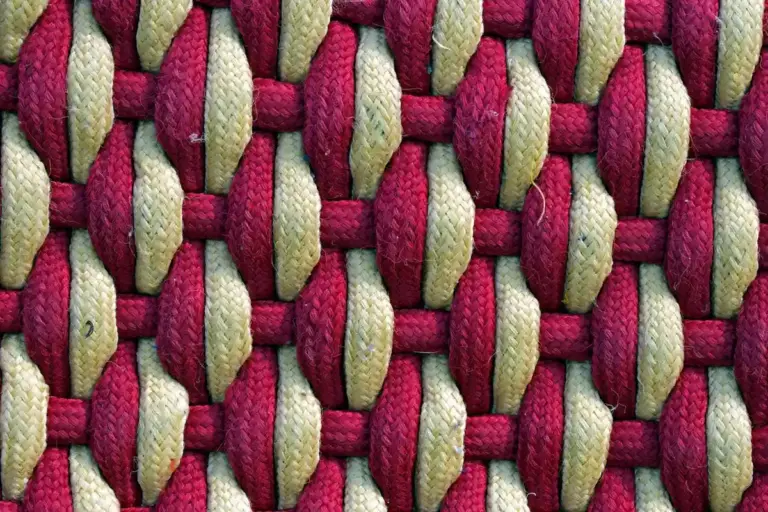 Close-up of a woven garage floor mat with red and beige strands.