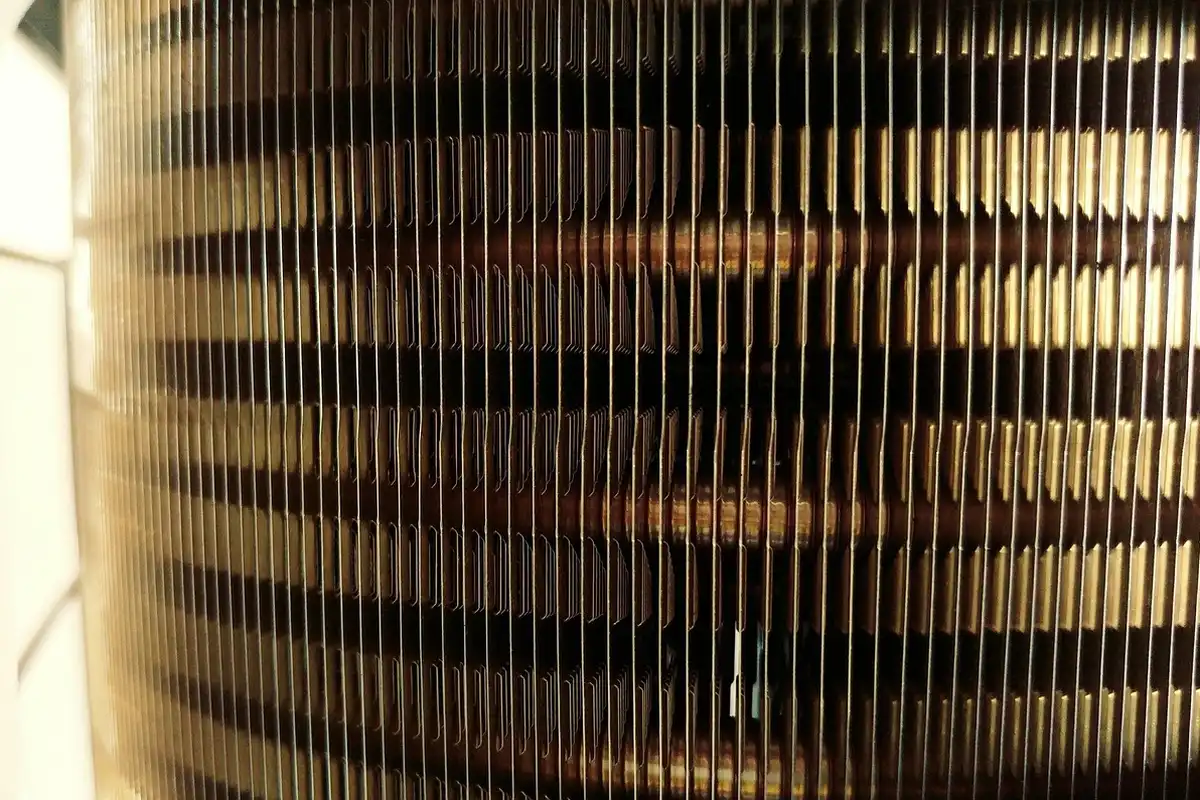 Close-up view of a finned heating element with narrow vertical fins, showing the metallic surfaces of a heater.
