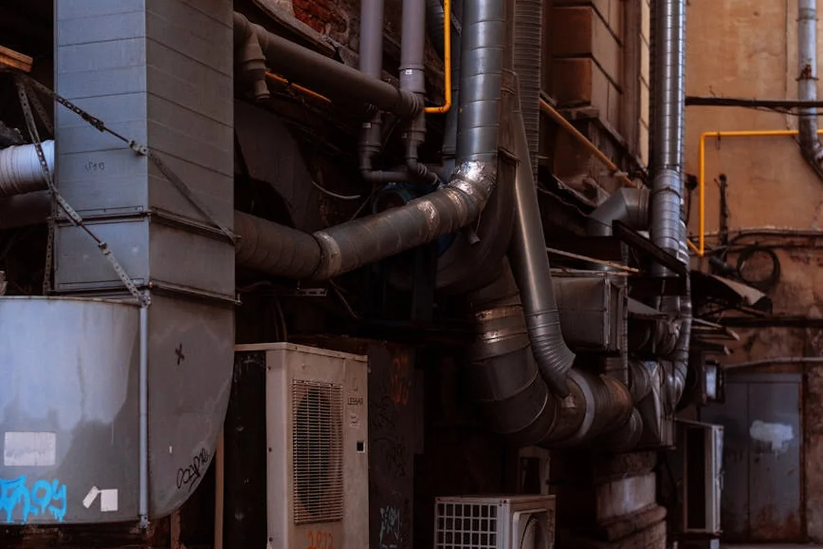 Industrial garage setting with exposed HVAC ductwork and pipes, illustrating complex installation