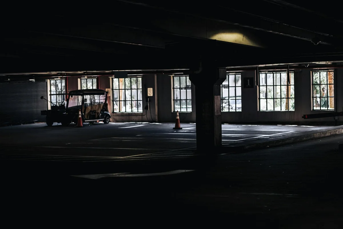 Dimly lit indoor garage with concrete support columns and a vehicle in the background, highlighting a space where roof durability and long-term wear are relevant.