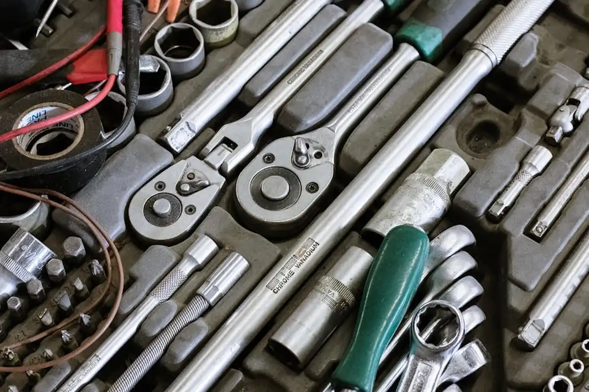A close-up view of a well-organized toolbox filled with metal hand tools, including ratchets, sockets, wrenches, and screwdrivers.