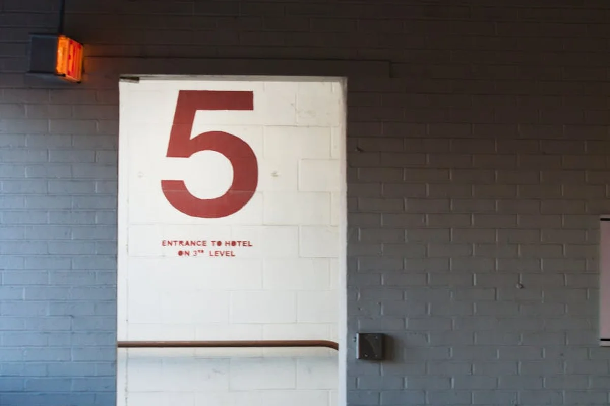 A white interior door with a large red number 5 on it in a dim hallway.