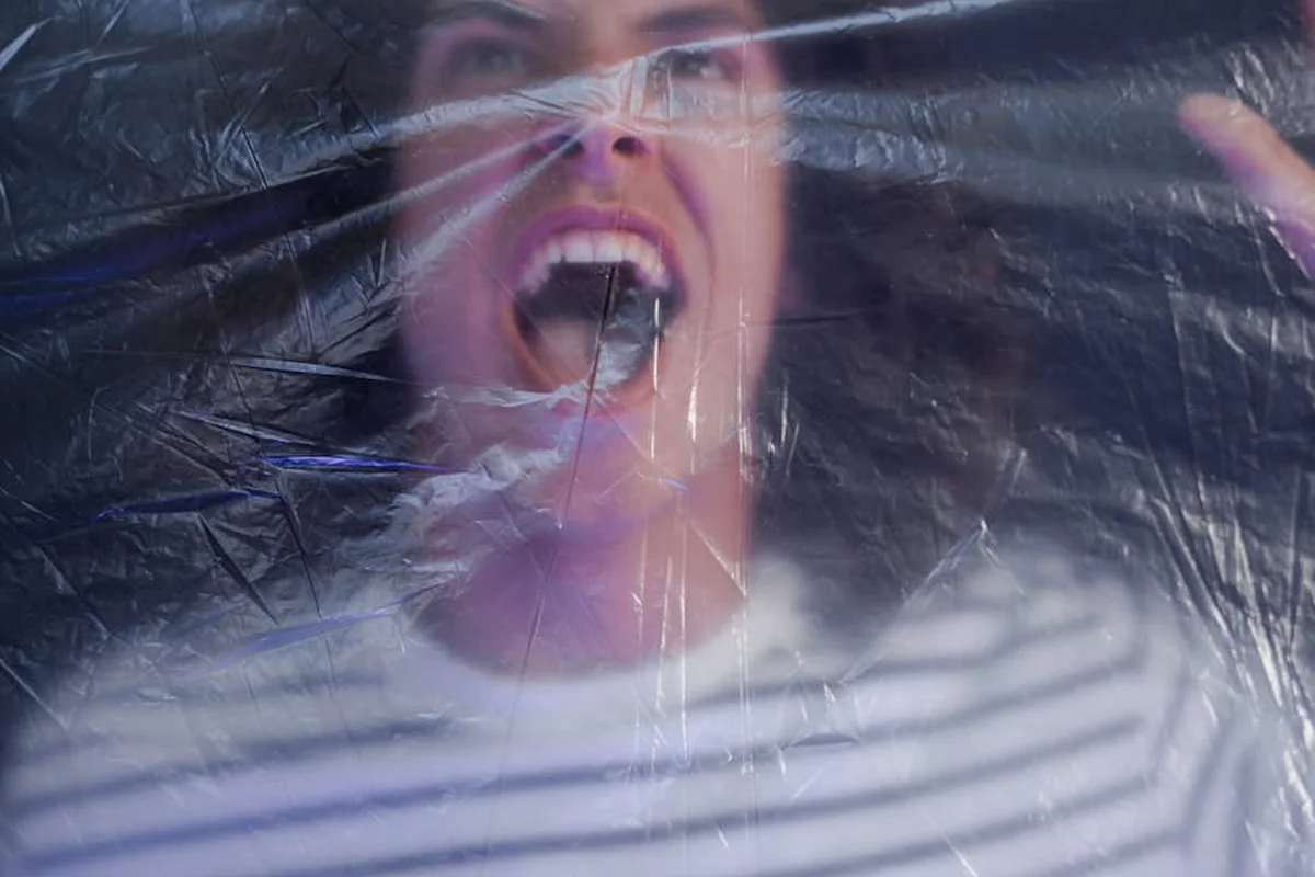 Close-up of a person behind a translucent plastic barrier, illustrating moisture-control concepts in garage construction