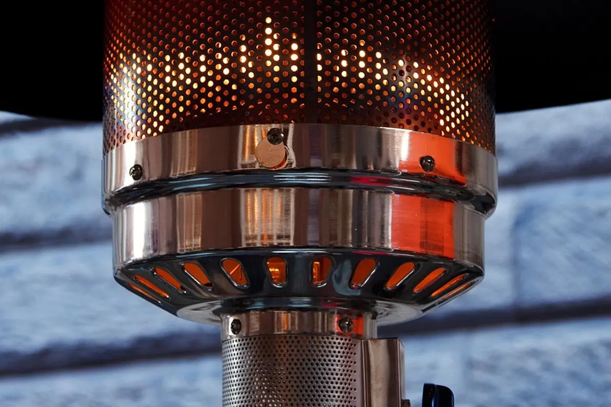 Close-up of a metal infrared heater burner assembly with perforated outer housing and chrome finish.