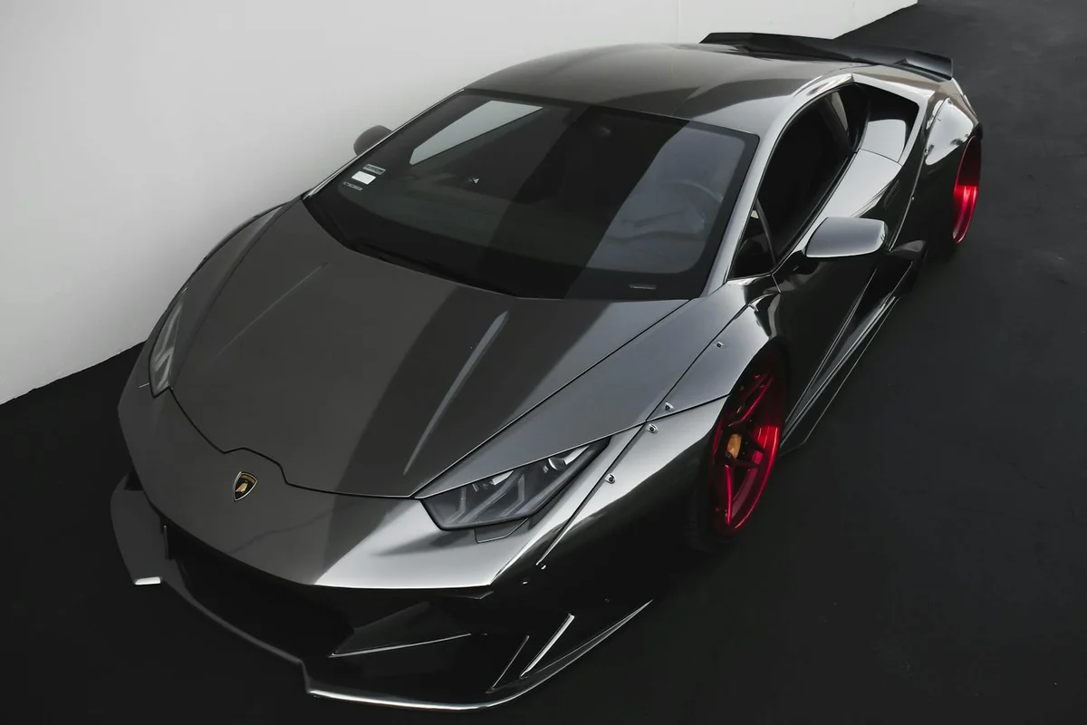 Top-down view of a silver Lamborghini with red wheels parked inside a clean, modern garage.
