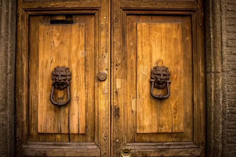 Two rustic wooden garage doors with decorative metal knockers.